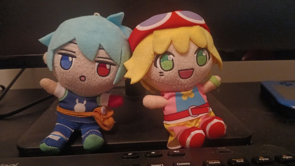 Sitting on my desk are two plushies of Puyo Puyo characters. On the left is Sig, and on the right is Amitie.