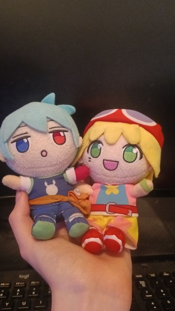 I'm holding two plushies with my left hand. On the left is Sig, and on the right is Amitie. Both characters are from Puyo Puyo.