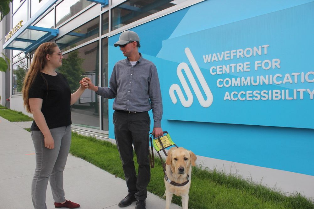 Intervenor-supported communication in action: A deafblind community member and an intervenor share a moment using tactile sign language during a community event supported by Wavefront Centre for Communication Accessibility.