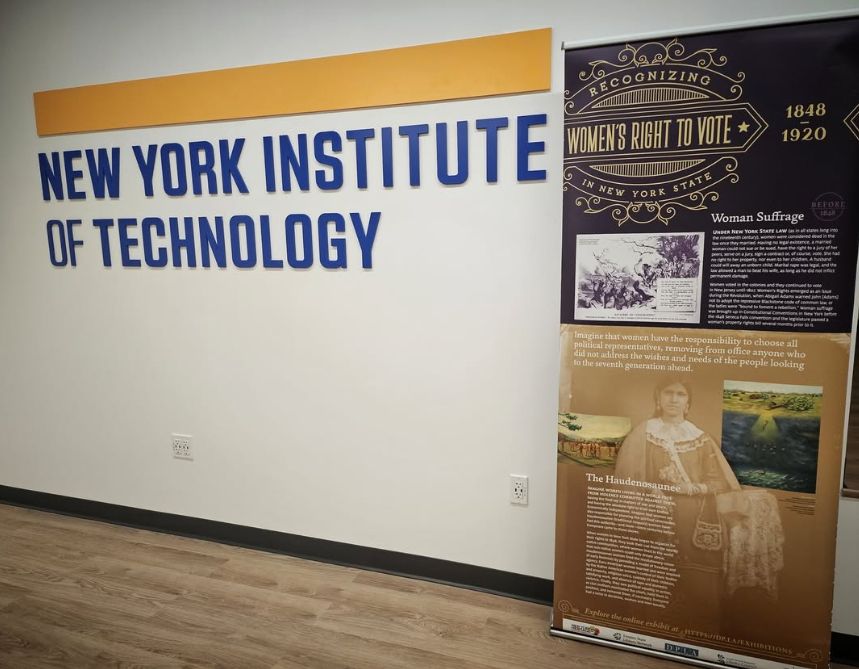 A five foot banner highlighting the beginning of the women's suffrage movement in New York State from 1848 to 1920 stands tall next to the NYIT logo in Salten's Reading Room.