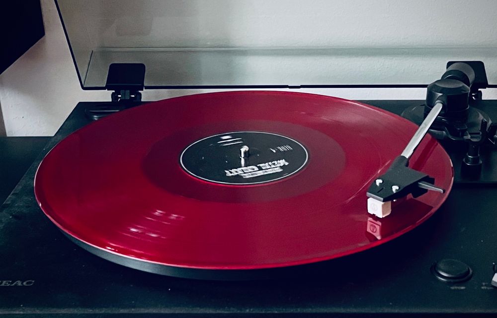 A deep-red vinyl record playing on a turntable 