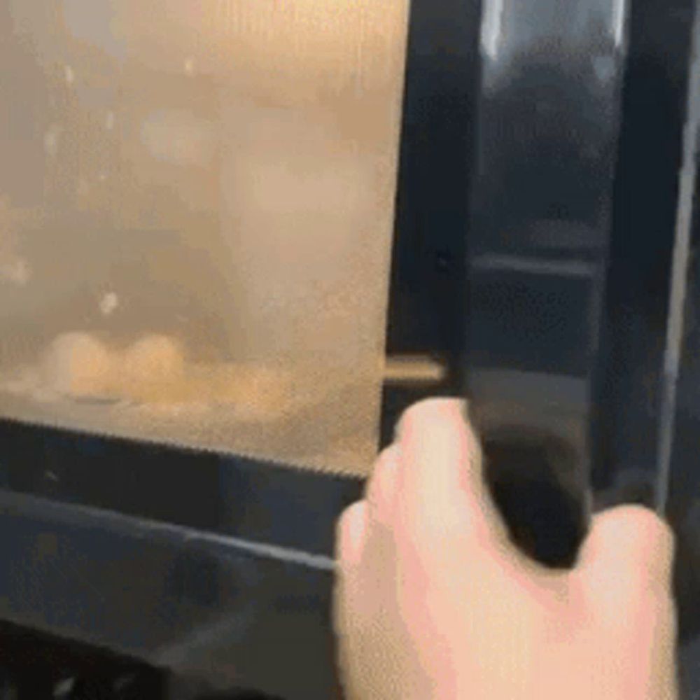 a person is opening a microwave with eggs inside of it .