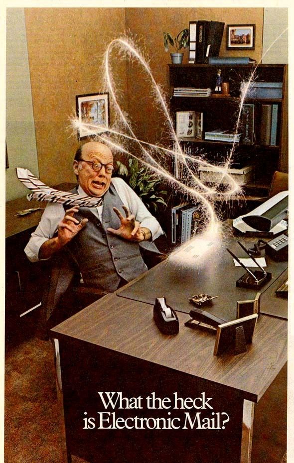 A 1980s or '90s ad featuring a businessman recoiling in horror at the sight of an envelope zipping around his office in a shower of electric sparks to land on his desk. The text below this image simply reads: "What the heck is Electronic Mail?"
