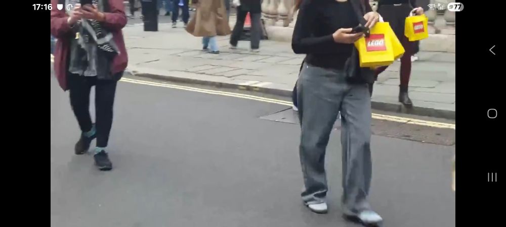 Screenshot from video showing two individuals walking past with LEGO bags.

Probably not part of the demonstration,  just shoppers.