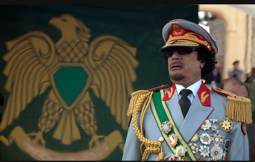 Image of Colonel Gadafi in garish uniform with lots of braiding and nedals