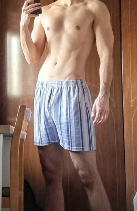 A lean AMAB looking body of someone taking a selfie. Their body is fit but not overtly bulky, somewhat lanky and thin, but still they clearly exercise regularly. 
