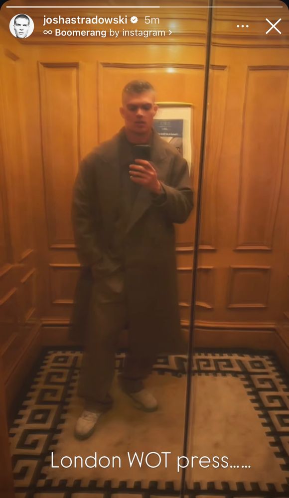 Insta selfie of Josha Stradowski in an elevator wearing a long coat with text 'London WOT press'