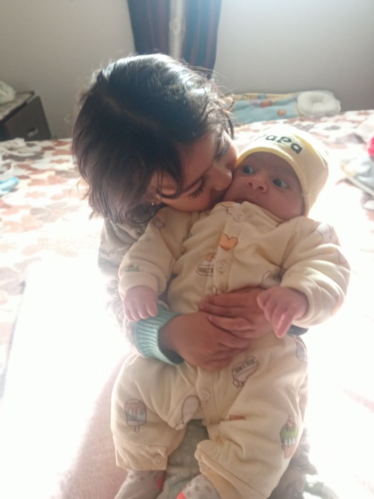 A young girl embracing her baby brother 
