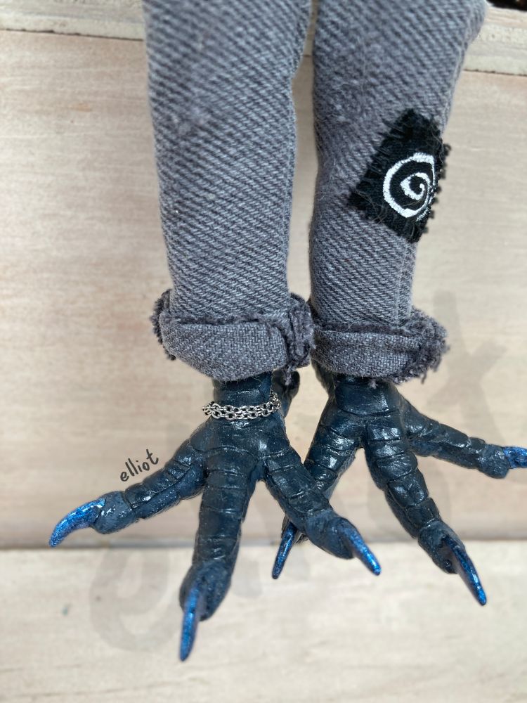 Zoom on the doll’s feet, they’re also wearing have shiny blue claws and a chain around one ankle