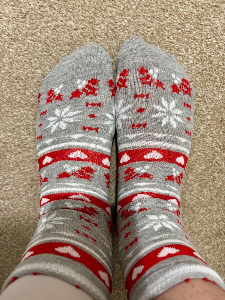 I’m wearing a pair of grey socks with a red and white pattern, including snowflakes, hearts, and holly 