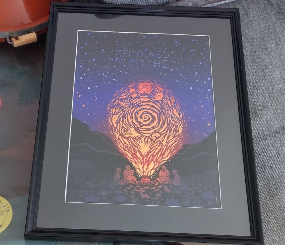 Version encadré dans un cadre noir de l''ffiche de l'illustratrice Valentine du Payrat inspiré par le podcast les mémoires du mythe. Elle représente quatre personnages de nuit autour d'un feu de camp. On voit danser dans les flammes les histoires qu'ils se racontent.