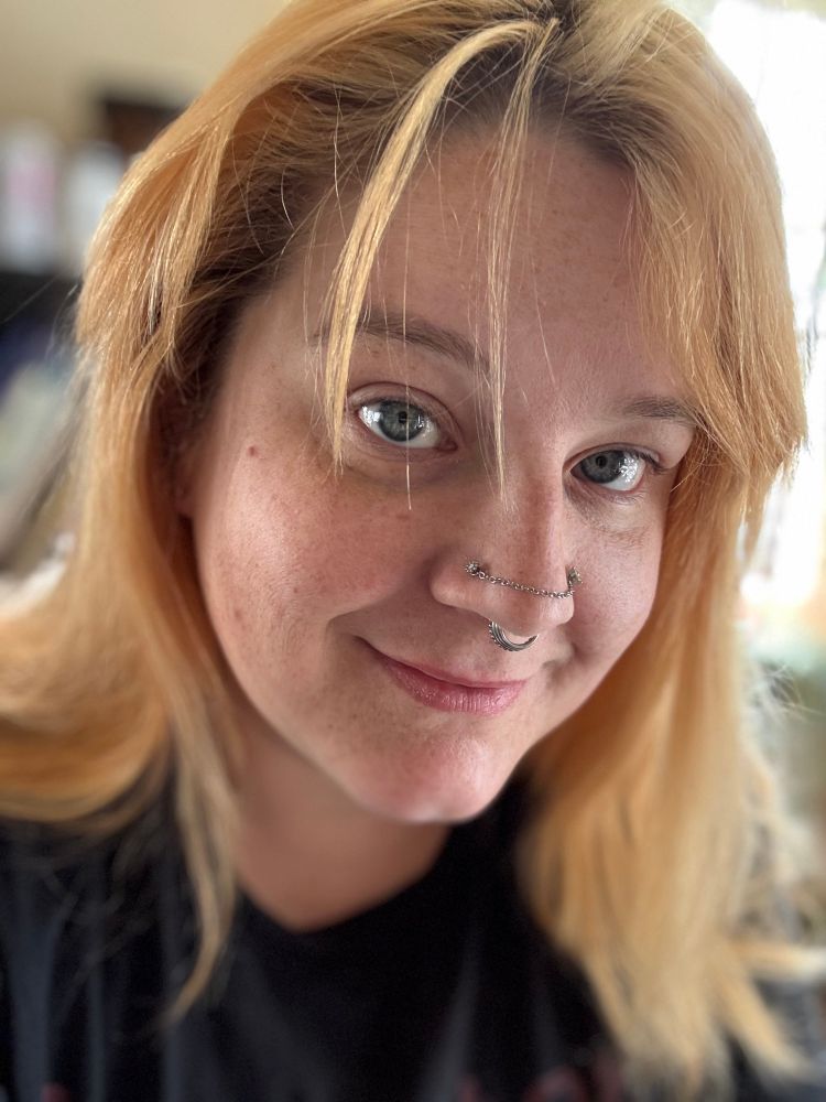 A bleach blond guy with piercings smiling 