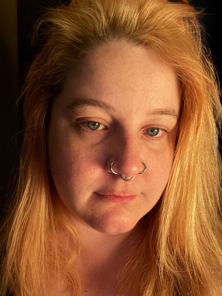 Selfie of a blonde guy looking exhausted. There are indeed three nose rings: one on each nostril and a septum 