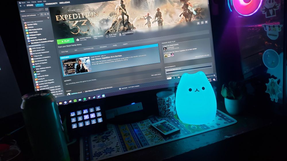 A picture of my pc setup with expedition 33 up on steam with a cat light shining cyan