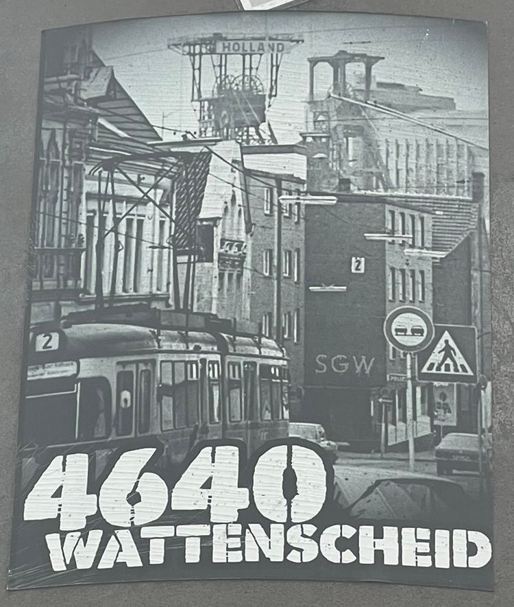 Aufkleber des SG Wattenscheid 09. Ein SW-Foto einer Straße in den 1970ern. Im Hintergrund die Zeche Holland. Vorne die Straßenbahn. Auf dem Kleber steht die alte Postleitzahl 4640 und Wattenscheid.