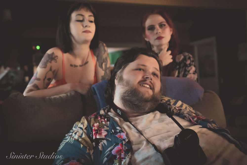 Dreamy photo of two femme people behind a large masc person