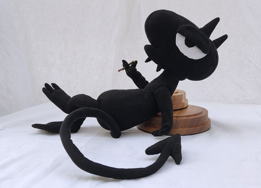 little black devil guy with large eyes. leaning comfortably and smoking...a stick (i dont smoke and i'm not letting him in the house)