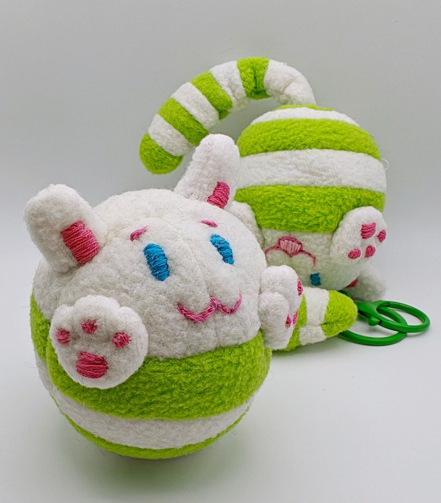 two round cat-like creatures. white with green stripes across body. 