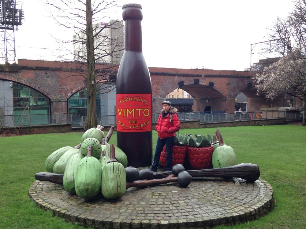 Me in Vimto park. There’s a huge Vimto bottle, maybe 4m high. And random giant fruit (strawberries, grapes and some random green fruit) on a brick dias which looks like a giant cheeseboard. 