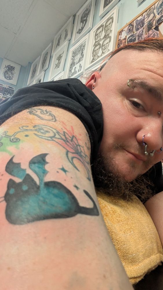 A spooky cat tattoo. The cat has bat wings and is in the loaf position.