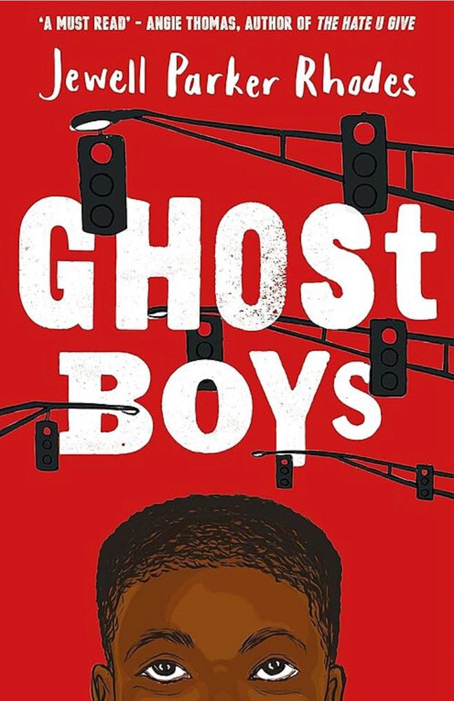 Cover of 'Ghost Boys'. The background is red and shows a young Black boy's face from the bridge of his nose up. He has short hair and is looking upwards. Above his head are silhouettes of streetlights and traffic lights which seem to branch into the space above the street. The title and author's name (Jewell Parker Rhodes) are written in white, the title across the middle of the book in large, mostly capital letters, the name at the top in smaller letters. At the very top, Angie Thomas, the author of 'The Hate You Give', is quoted, saying 'A must read'.