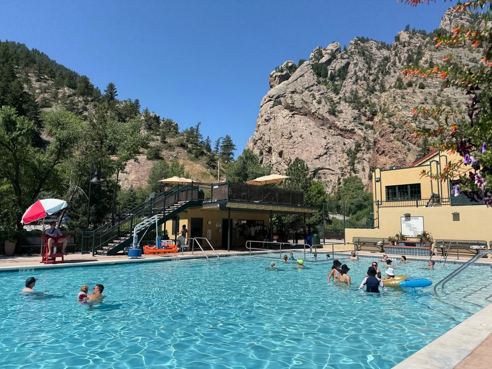 A beautiful swimming pool in the mountains in Colorado. People swimming and floating in the pool.