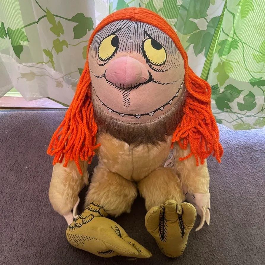  Plüschtier mit roten Wollhaaren zu Die wilden Kerle von Sendak mit verwirrtem Grinsen bei dem die Zähne sichtbar sind und gelben Augen