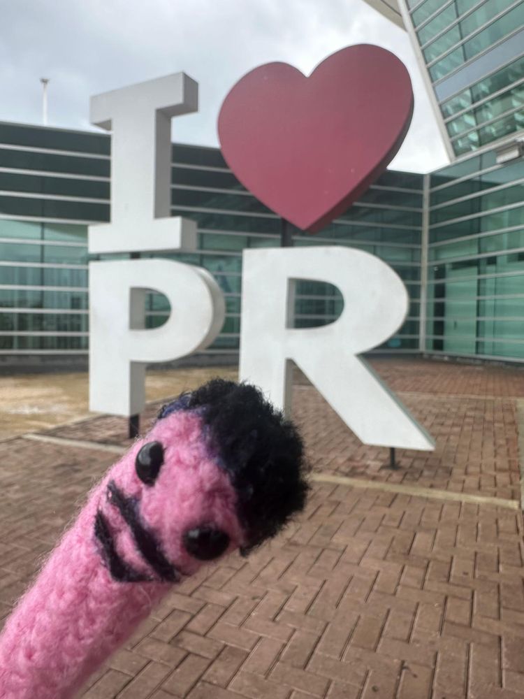 Crochet bad bunny worm in front of sign letters that say "I ❤️ PR"