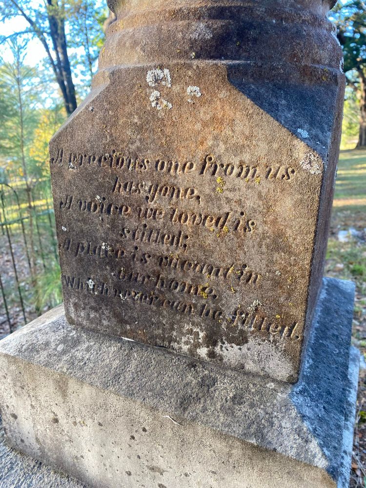 an old tombstone that reads “A precious one from us has gone, a voice we loved is silent; a place is vacant in our home, which can never be filled.” 