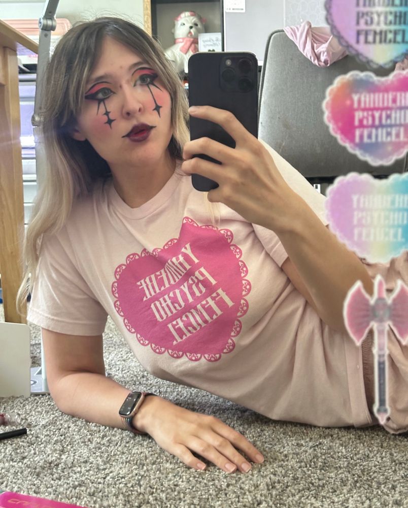 clown girl wearing edgy tshirt that says yandere psycho femcel with a pink lace heart