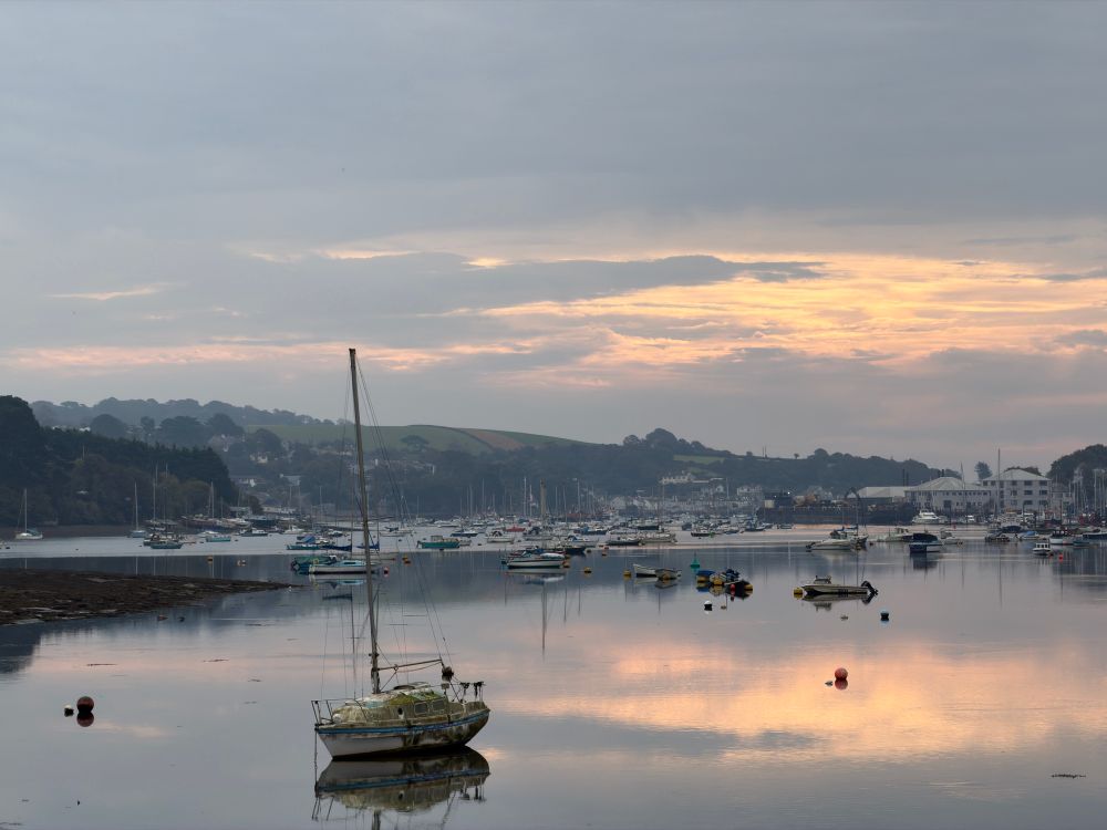 View from the Muddy Beach cafe in Penryn. Boats on the water and a streaked goldish sky.