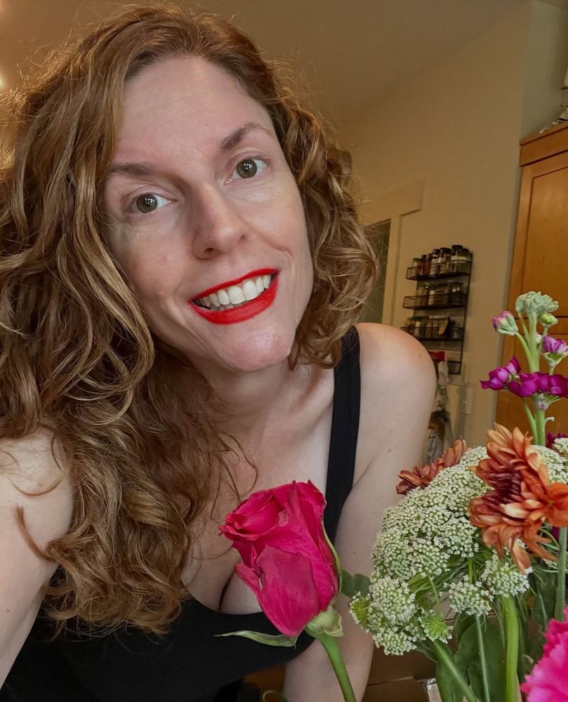 Jendia Gammon smiling behind a bouquet of mixed flowers.