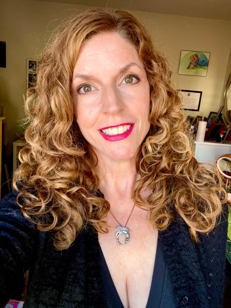 Jendia Gammon in a black V-neck dress and black cardigan, wearing a silver dragon necklace.