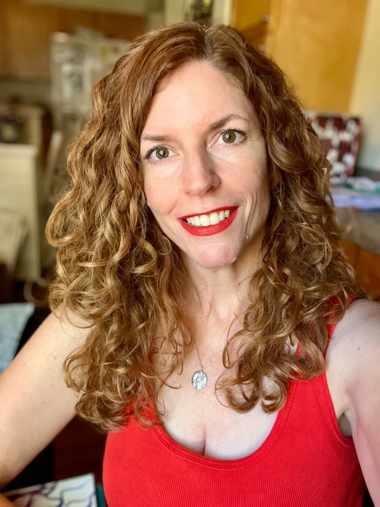 Jendia Gammon in a bright red tank top wearing a small silver sand dollar necklace.