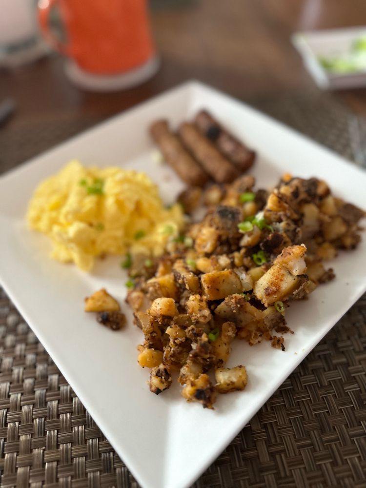 Home fries, scrambled eggs, and turkey sausage on a plate. 