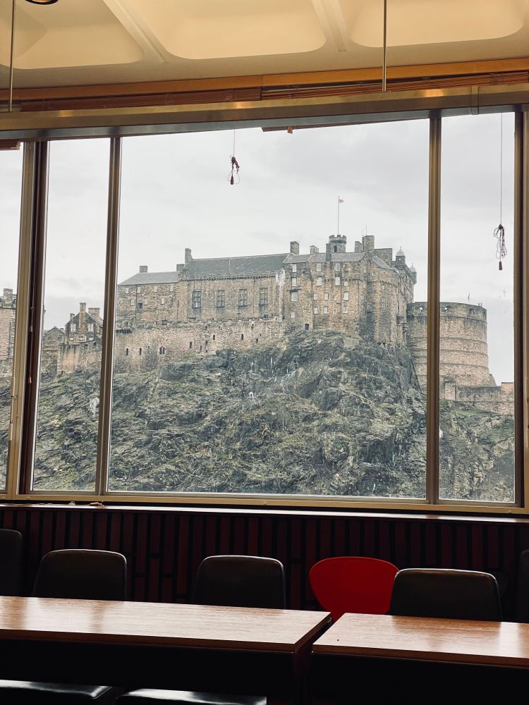A window with the south face of Edinburgh Castle framed, very close by and filling the whole view.