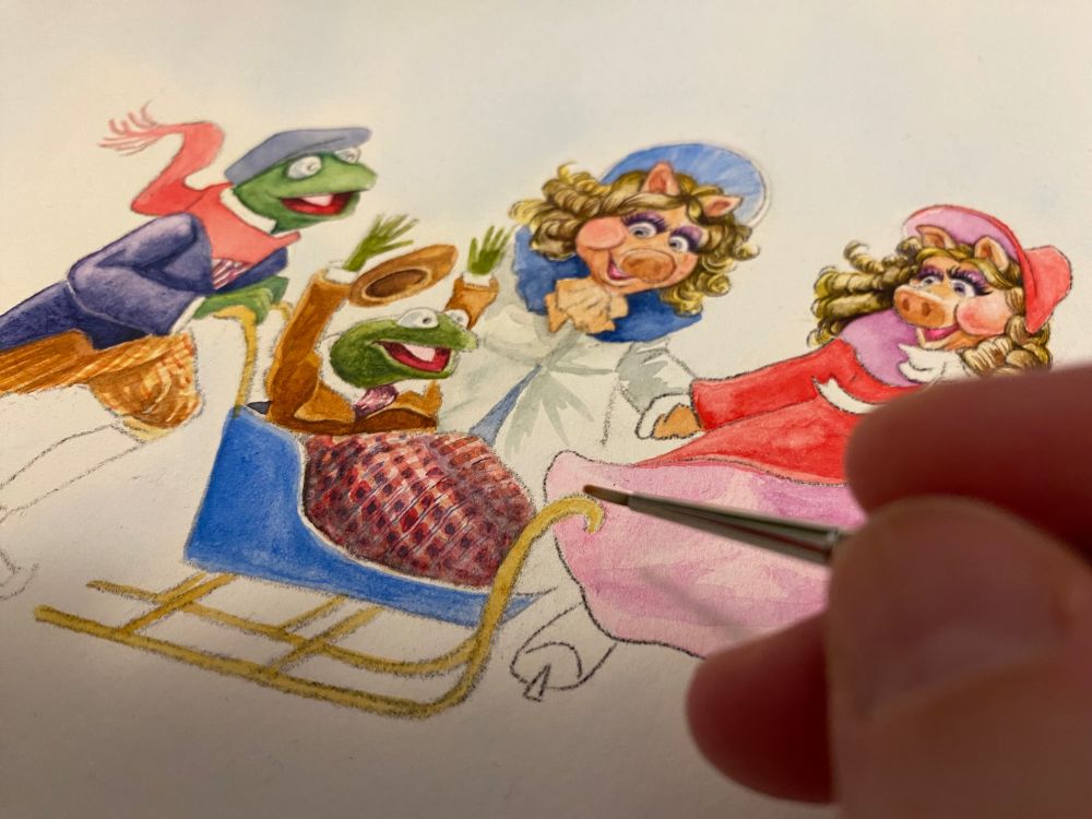 Watercolour illustration in progress of Peter, the older brother of Tiny Tim in The Muppet Christmas Carol, on ice skates, pushing Tiny Tim in a small sled. Their pig sisters, Belinda and Bettina are skating alongside them. Everyone looks happy and Tiny Tim has his arms up in the air, in excitement.His hat has flown off. The painting is unfinished. A hand hovers above, with a paintbrush.