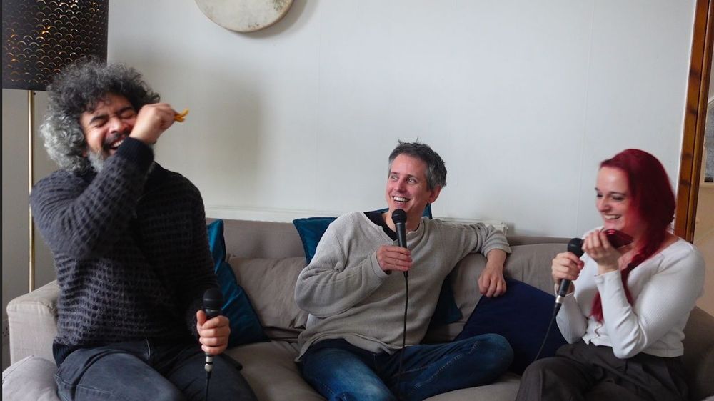 Masud, Chris and Sooz on a sofa holding mics laughing very hard at something one of them said (not sure what but it looks hilarious)