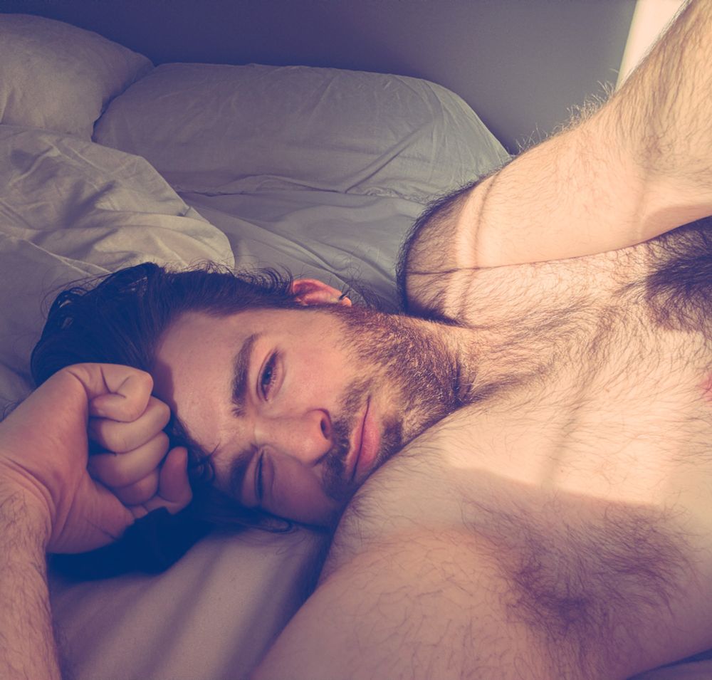 A well lit selfie of a hairy shirtless man 