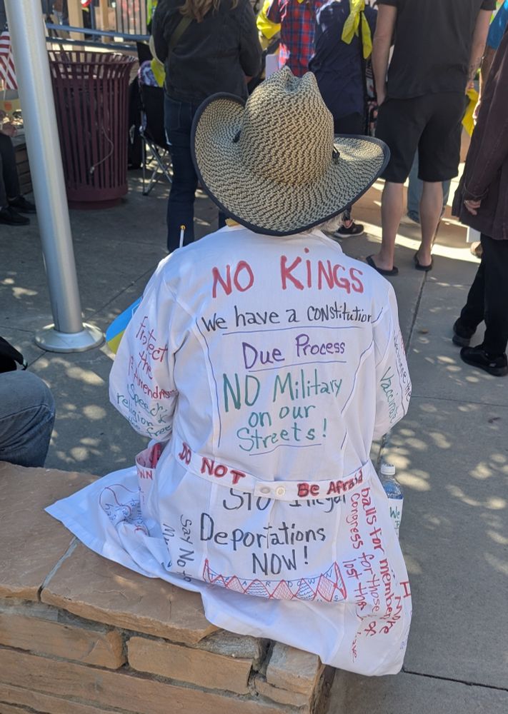Protester wearing a medical smock with multiple pro-democracy anti-Trump slogans