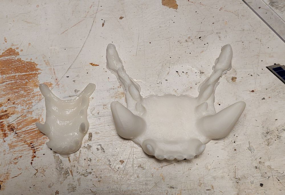 Two sets of creature teeth made of off-white plastic. On the left is the set for a regular-size wolf; on the right is a monster set about 3x as large.
