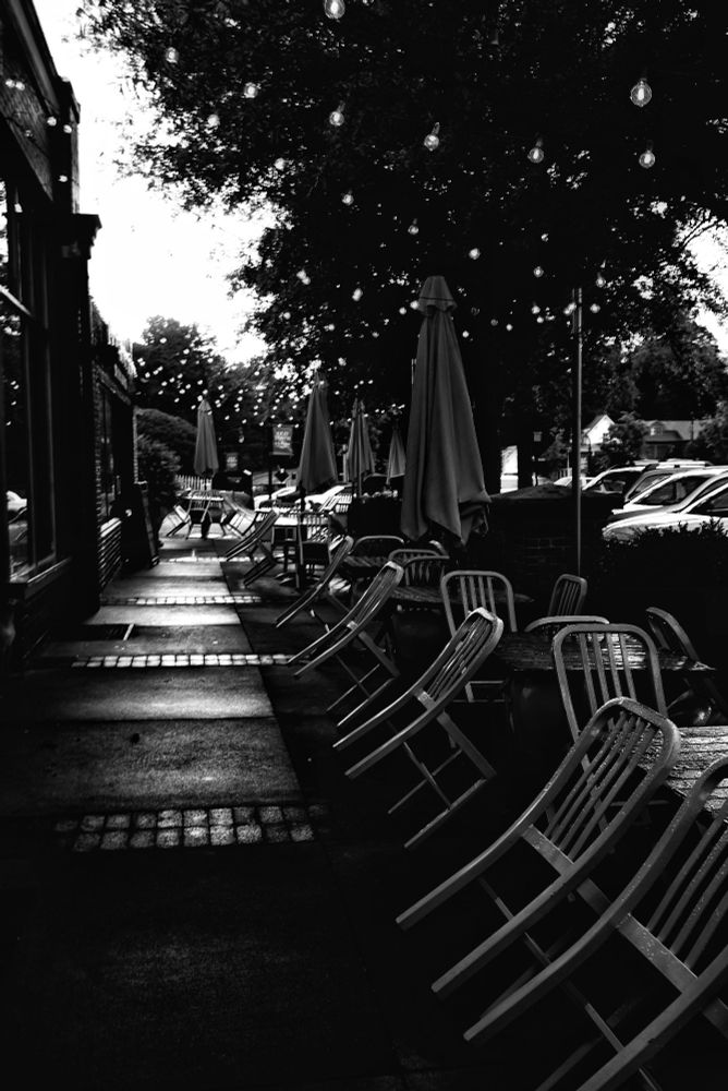 restaurant patio, sidewalk bisecting store fronts and leaning chairs with closed umbrellas