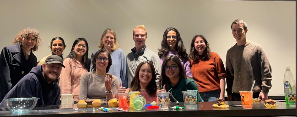 Members of the LEmo lab stand in a group behind a counter with various baking supplies