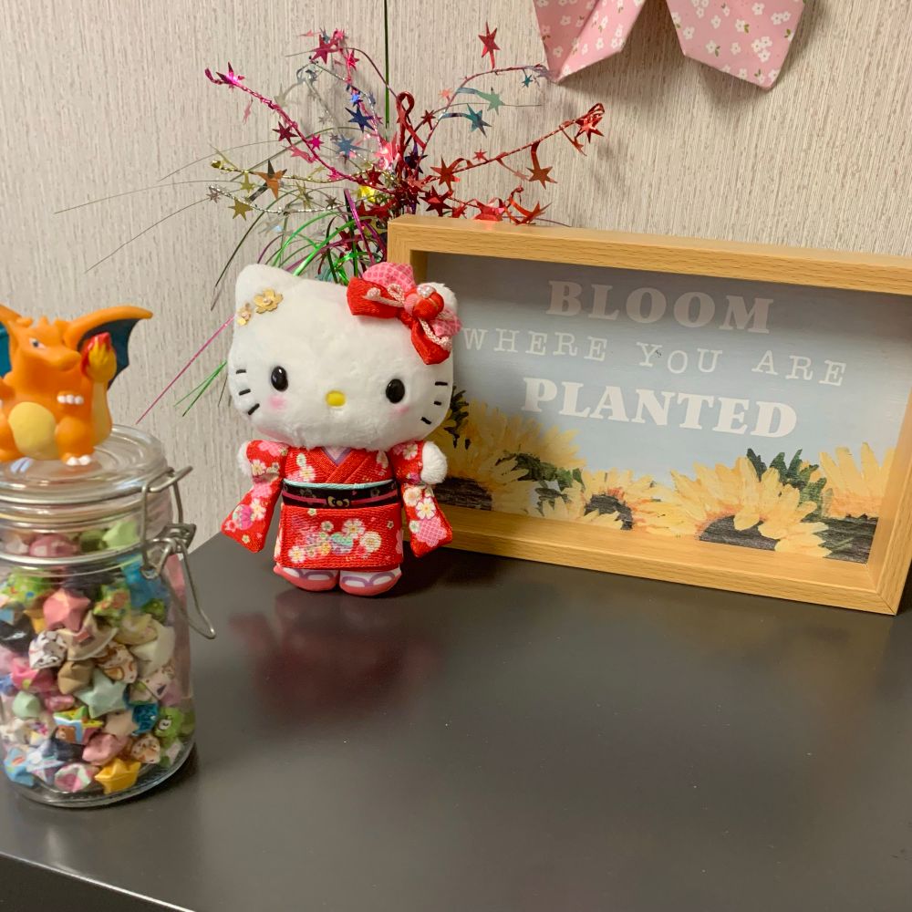 Hello Kitty plushie next to a sign 