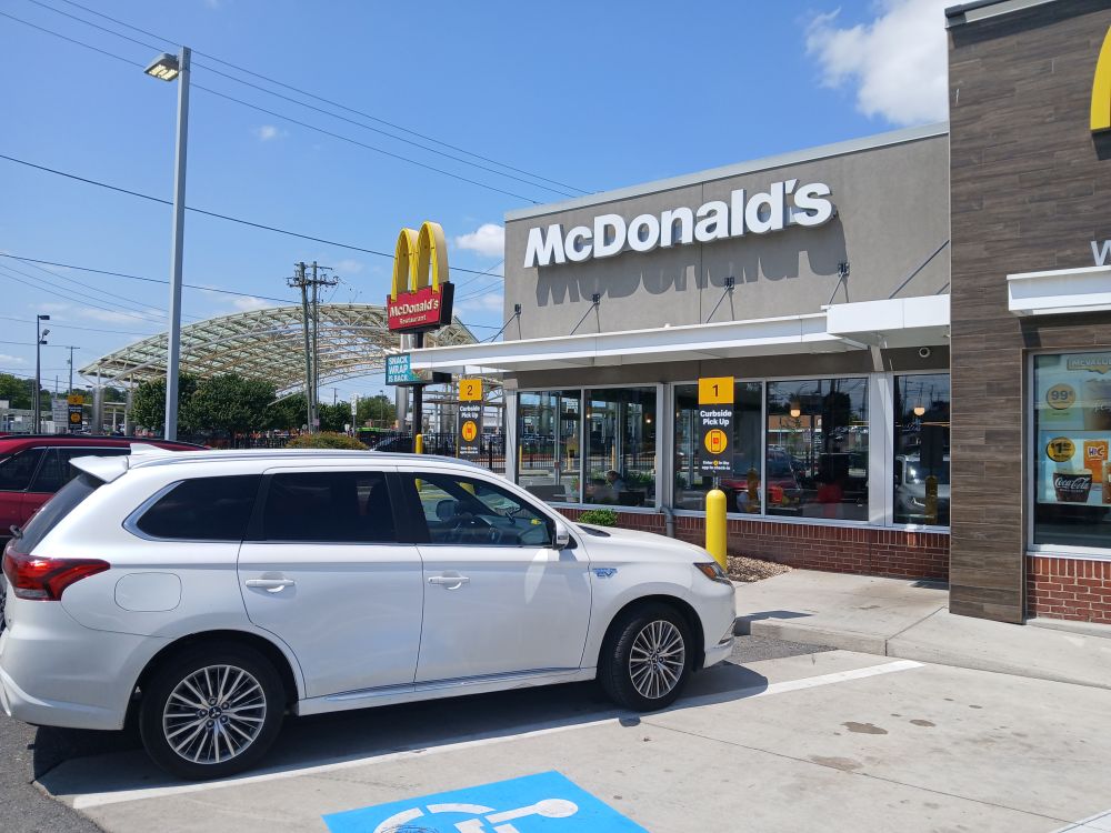 Just outside Takoma Park, Maryland, a McDonalds parking lot with vertical signs at the head of each space. Behind the parking spaces, the McDonalds building. In background, New Hampshire Avenue.