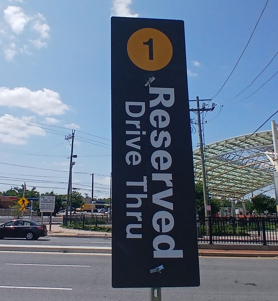 Closeup of vertical sign at head of parking space. Under the number 1, the text "Reserved Drive Thru."