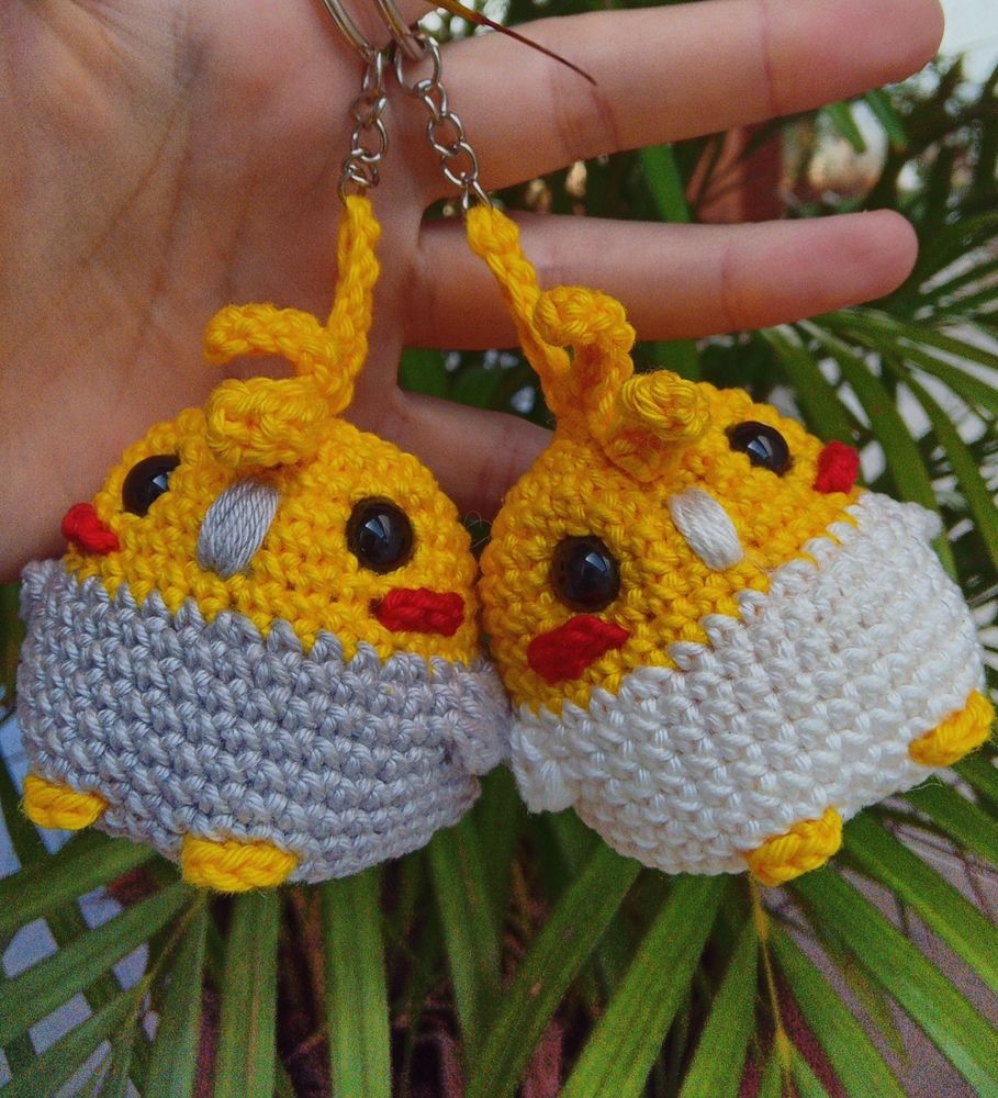 Foto de dois amigurumis de calopsita. A da esquerda é cinza com amarelo e a da direita é branca com amarelo 