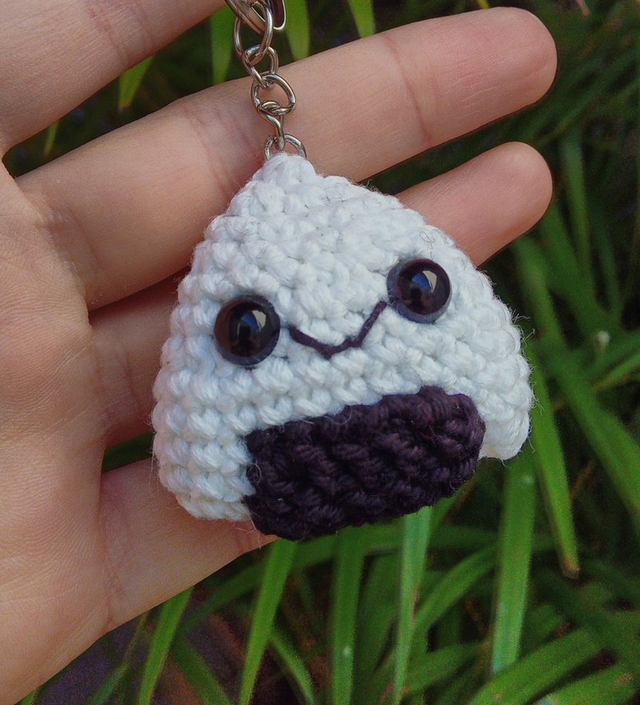 Foto de um chaveiro de amigurumi de um onigiri sorridente 