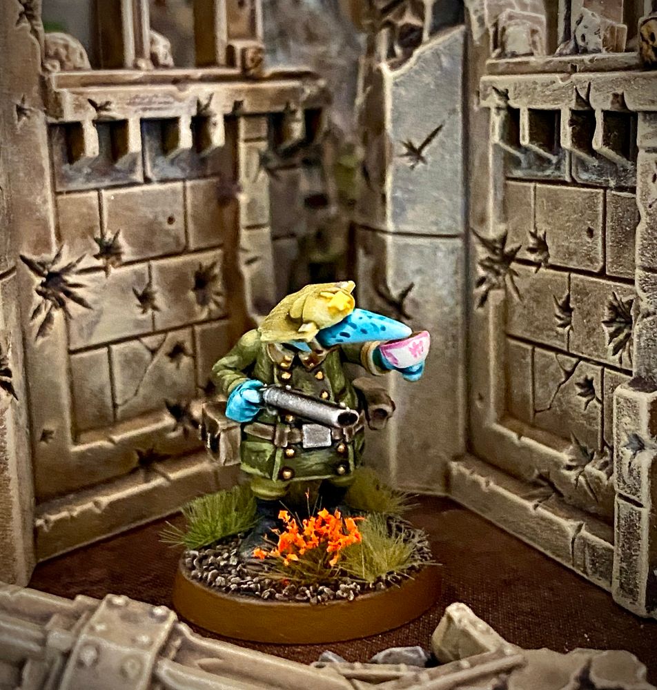 Blue-skinned Quar Crusader officer in green uniform with shotgun and white teacup with pink decoration stands in front of ruins with bullet holes.
