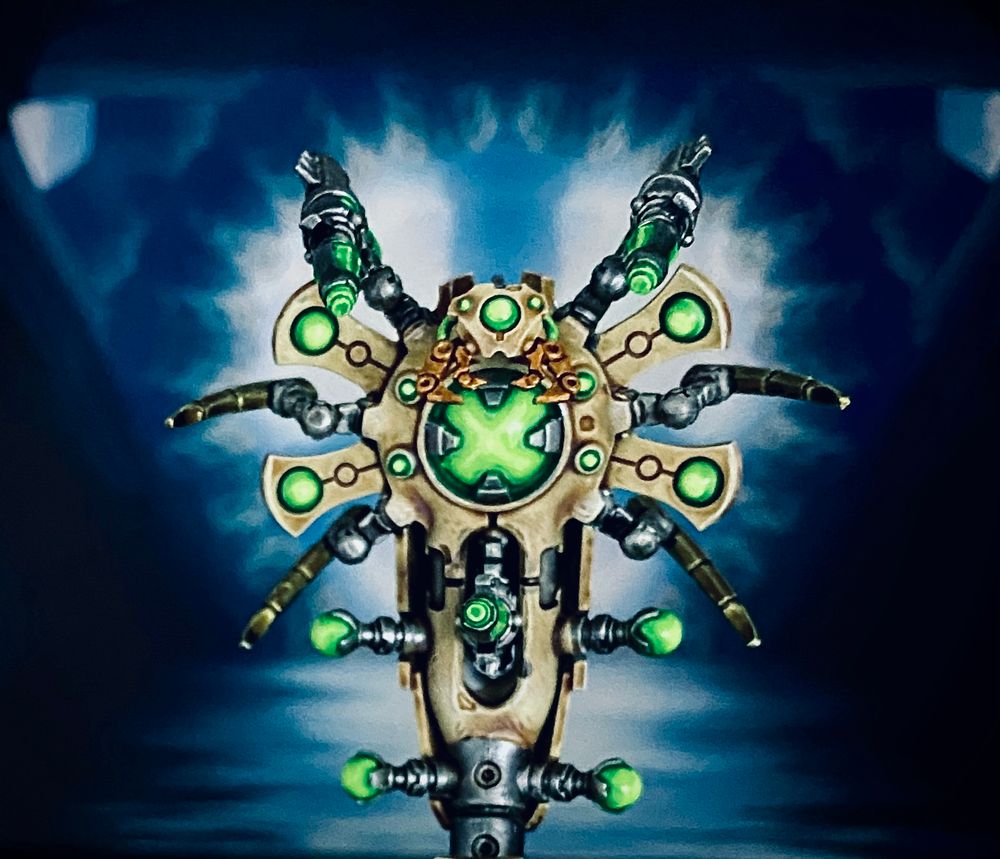 “Boo!” 
If she isn’t controlling the energy flow of her Monolith’s power matrix crystal Wraith senu-chemet-fedu likes to roam the tomb and startle intruders.”

Bone colored Necron Canoptek Construct with green energy orbs in front of a blueish sci-fi backdrop by Jon Hodgson.